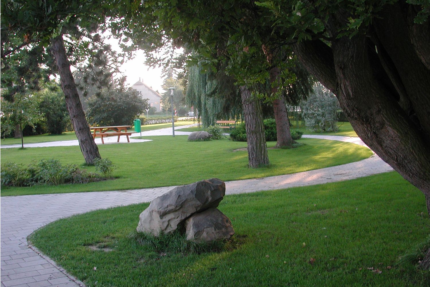 A well-kept park with trees, paths and benches.