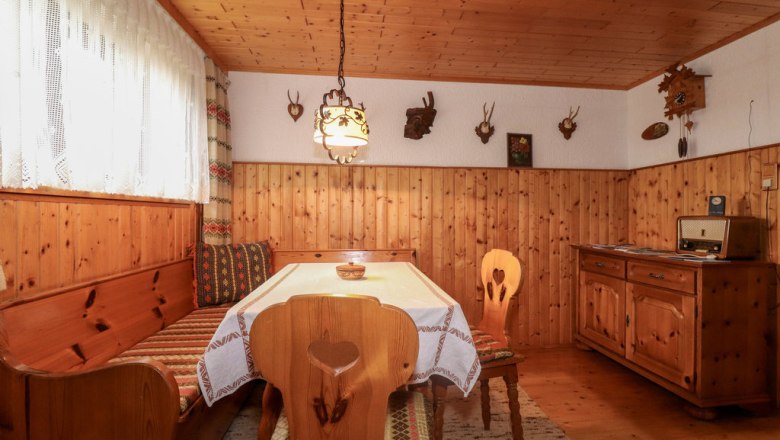 Cozy cellar room with wooden furniture, corner bench, table, radio and hunting trophies on the wall.