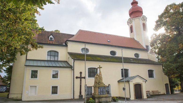 Heiligeneich parish church with statue and cross in the foreground.