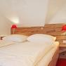 Guest room with wooden bed and red lamps.