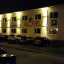 Night shot of an illuminated motel with the lettering 'Hainburg Motel' and parked cars in front of it.
