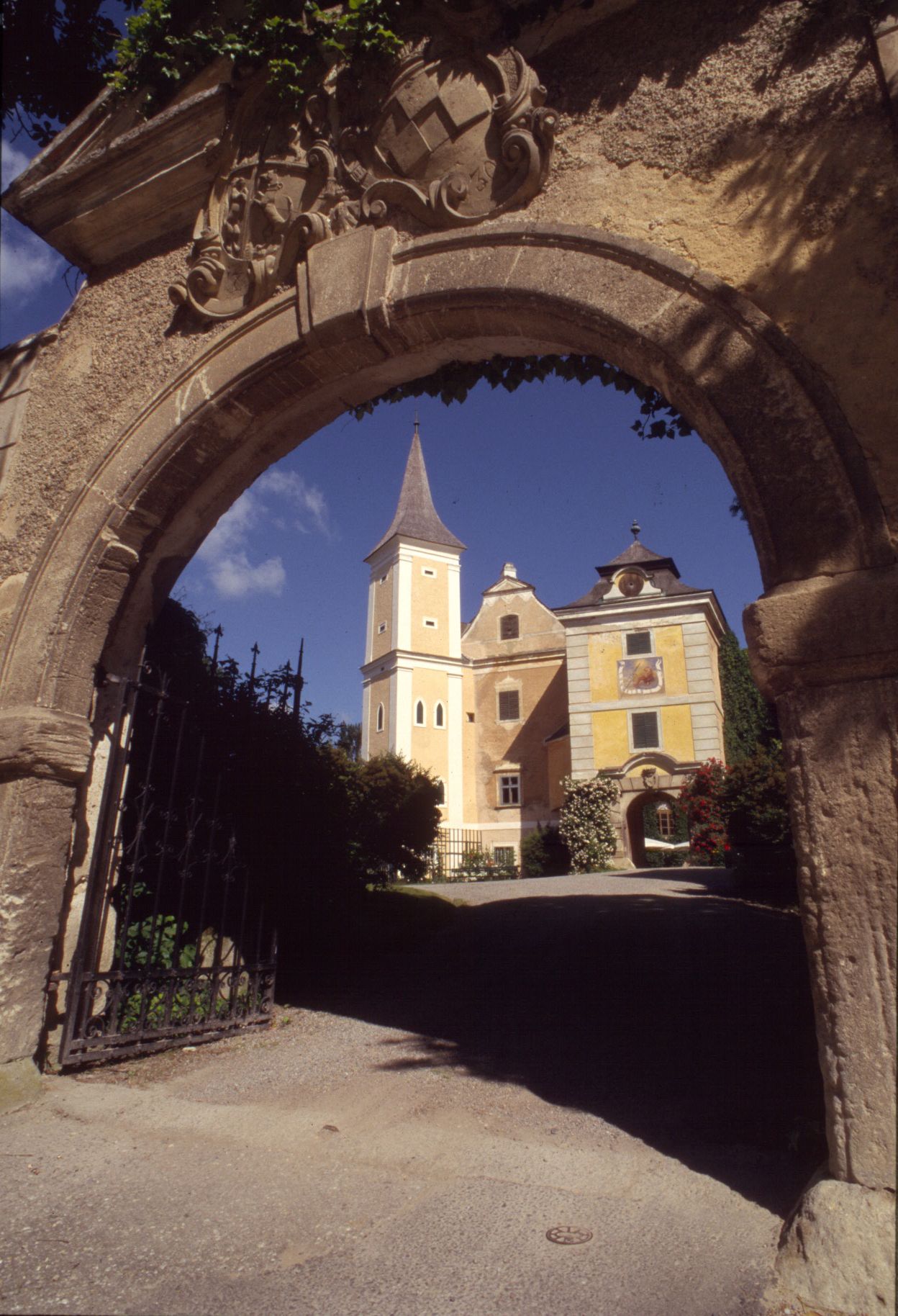 Historic building with tower seen through a stone archway.