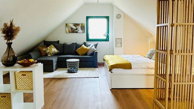 Cozy attic apartment with sofa, bed and wooden floor.