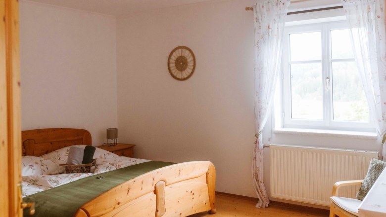 Cozy double room with wooden furniture and window with curtains.