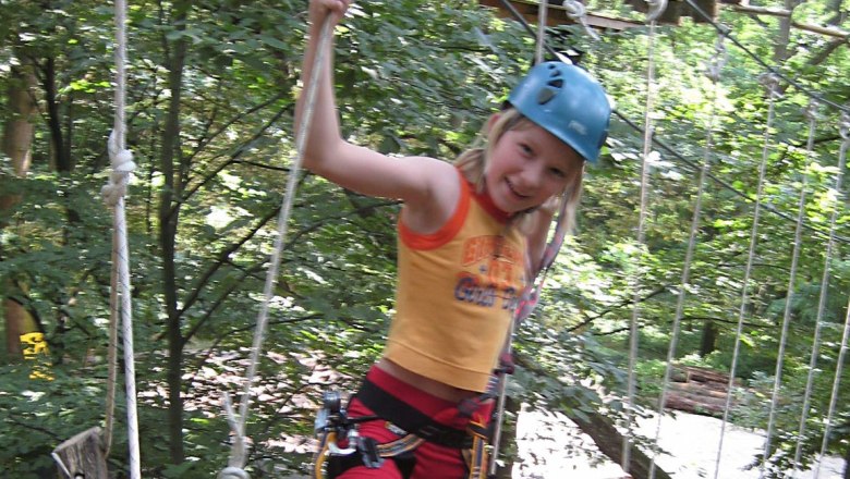 Child with helmet in the climbing park on a rope course.
