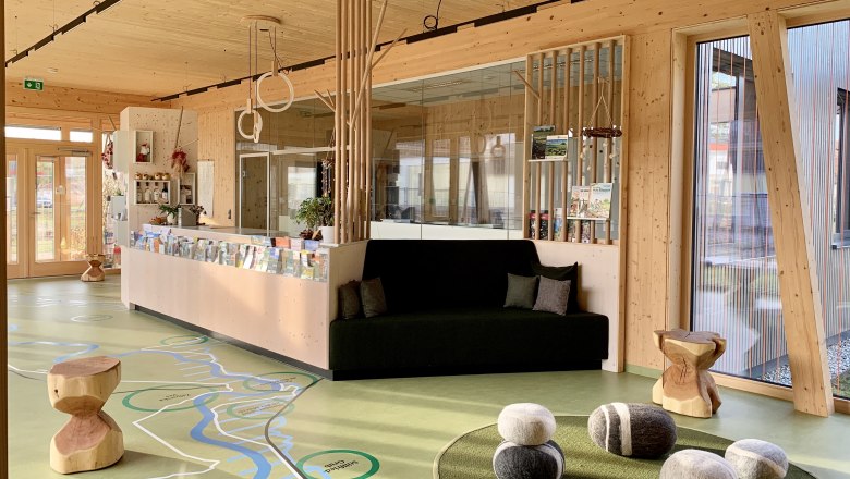 Interior view of a modern foyer with wooden elements, a bench and decorative stones on the floor.