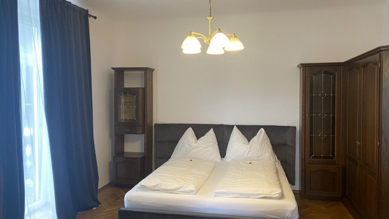 Cervo d'oro Apartment, © Cervo d’oro Appartement Bedroom with double bed, dark curtains and wooden wardrobes.
