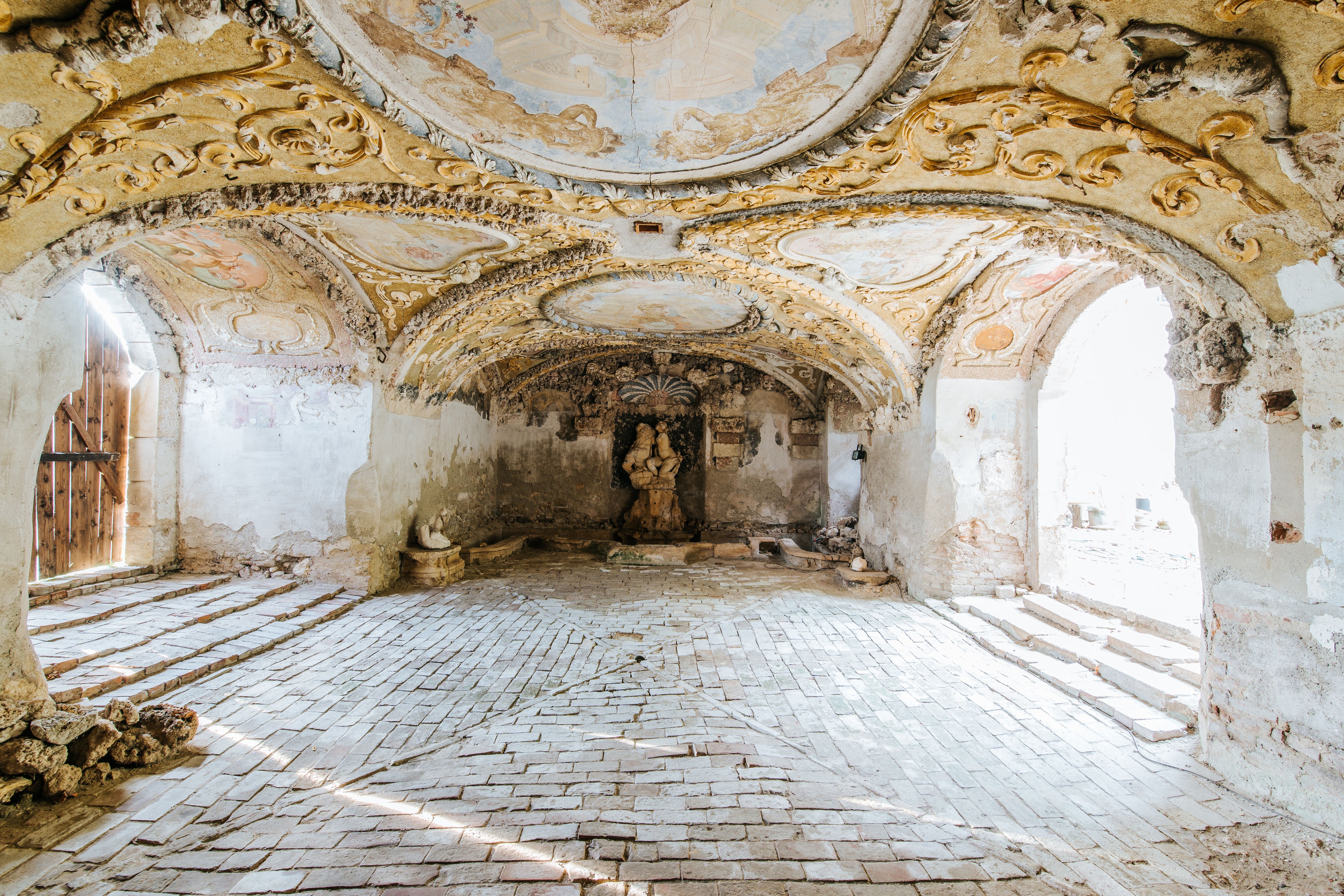 Historic room with ornate ceilings and a statue in the center.