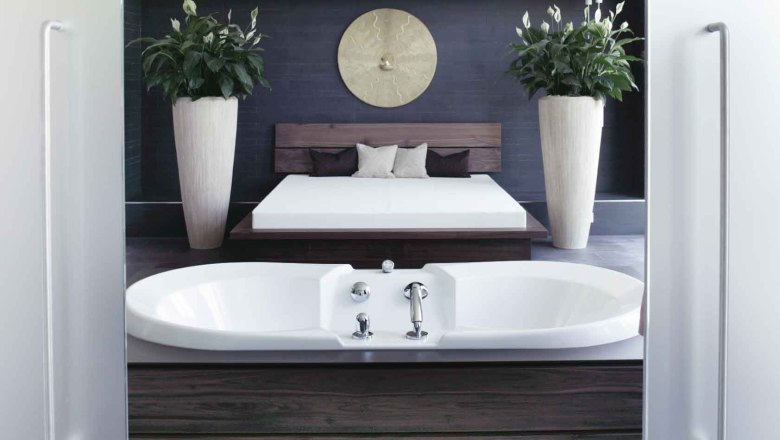Modern spa area with bathtub, bed and plants.