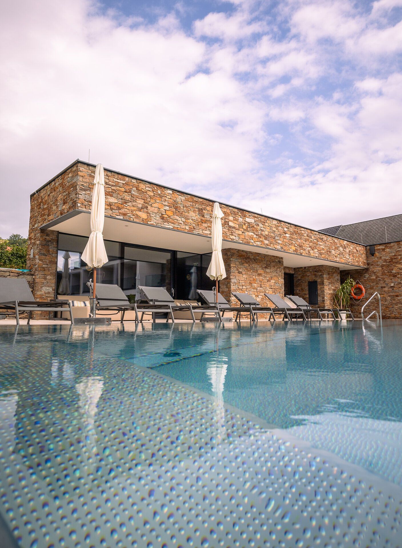 Exterior view of a modern hotel with pool and sun loungers.