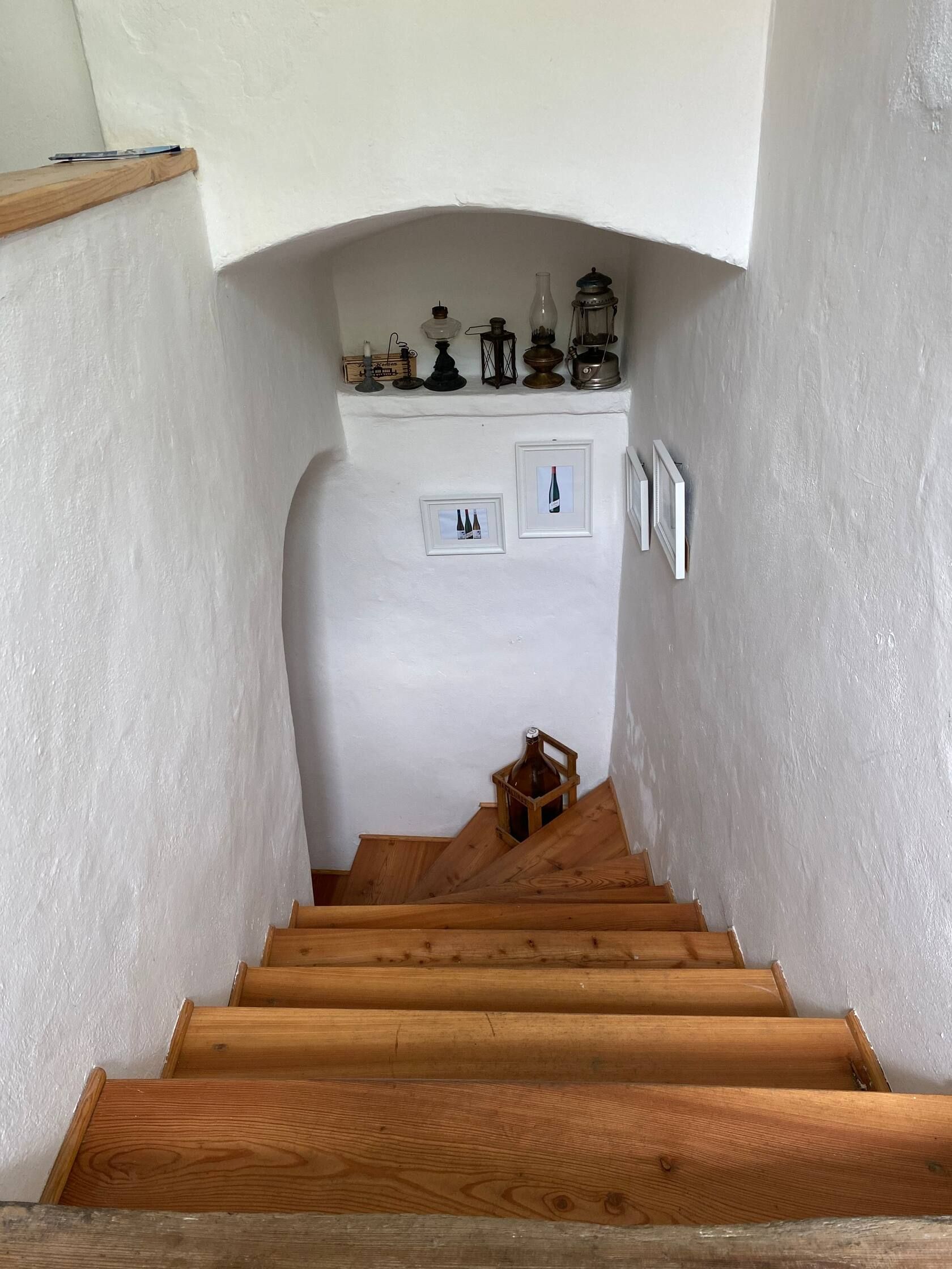 Wooden staircase in a white stairwell with decorations and pictures on the walls.