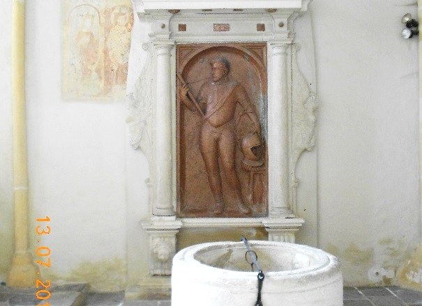 Tomb with relief and baptismal font in a church.