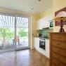 Bright kitchen with parquet floor, cupboard, stove and large glass door to the terrace with awning.