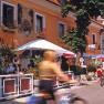 Cyclists in front of a hotel with a terrace and parasols.