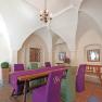 Interior view of a room in the Renaissance Hotel Raffelsberger Hof with vaulted ceiling, wooden table and chairs with purple and green upholstery.