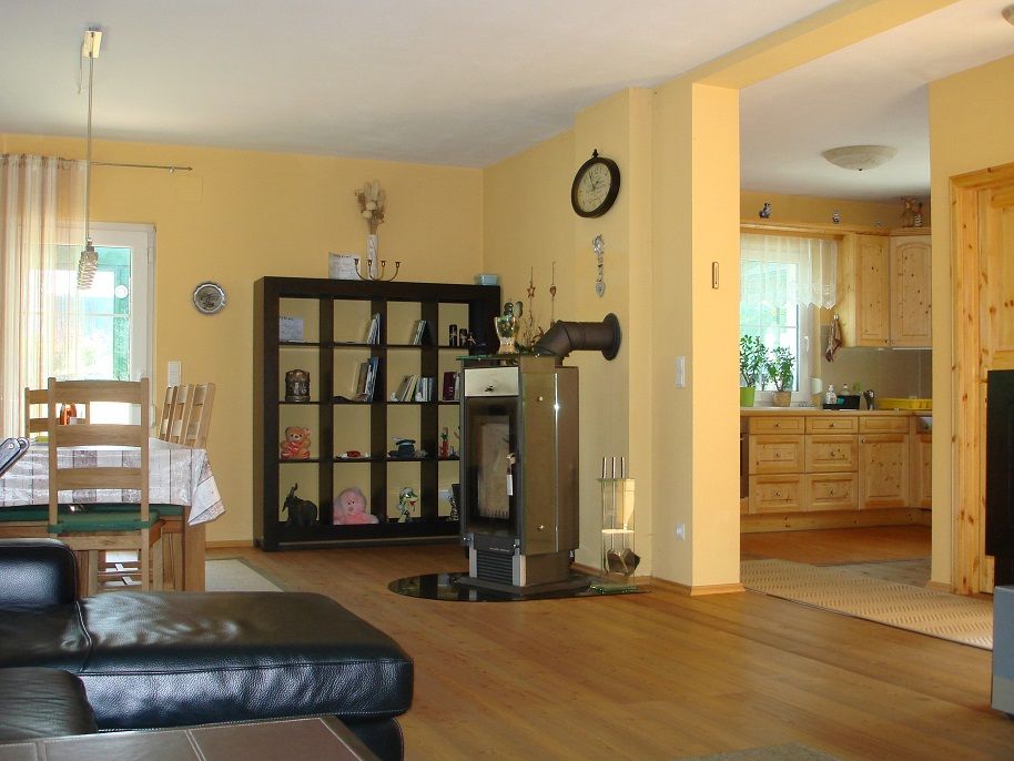 Kitchen-living room with wooden furniture, dining table, shelving, fireplace and open kitchen.
