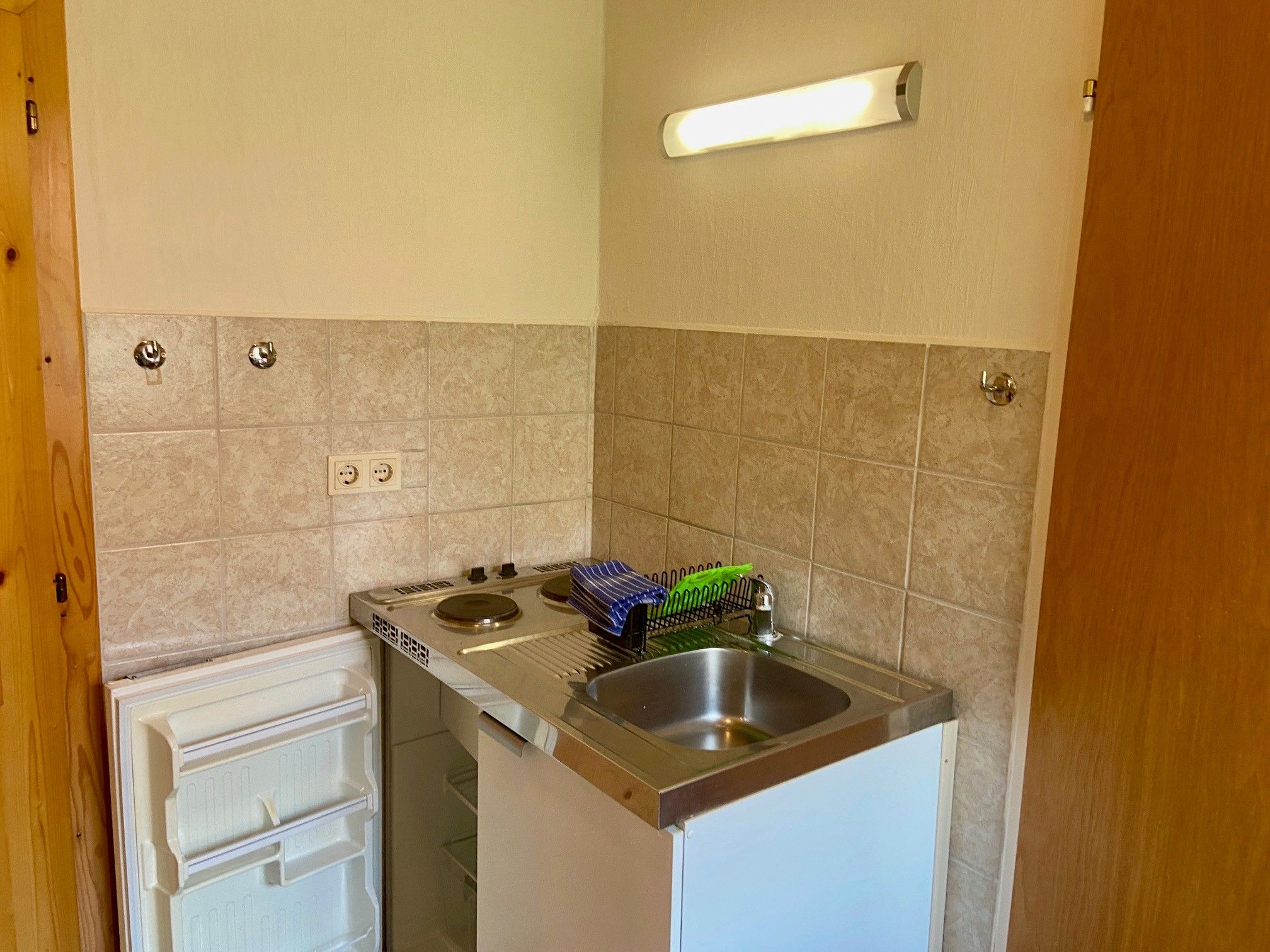 Small kitchenette with sink, stove and fridge.