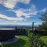 A round whirlpool in the garden with a view of a vast landscape and blue sky.
