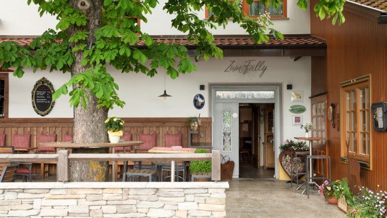 Entrance to a country inn with wooden furniture and plants.