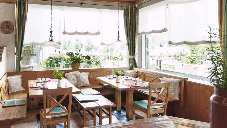 Cozy breakfast room with wooden furniture and large windows overlooking a terrace.