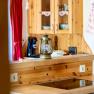 Wooden kitchen sideboard with ceramic hob, lantern on the counter, box and red curtain in the background.
