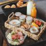 Breakfast tray with bread rolls, croissant, milk, juice, yogurt, eggs, cold cuts and vegetables.