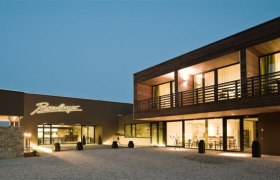 Modern building of the Rosenberger winery at dusk with illuminated lettering.