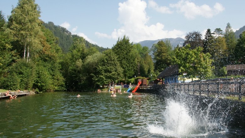 People swim and play in the Seebachbad Lunz am See, surrounded by trees and mountains.