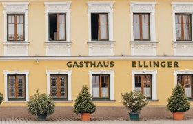 Fa&ccedil;ade of a yellow inn with the inscription 'Gasthaus Ellinger'.