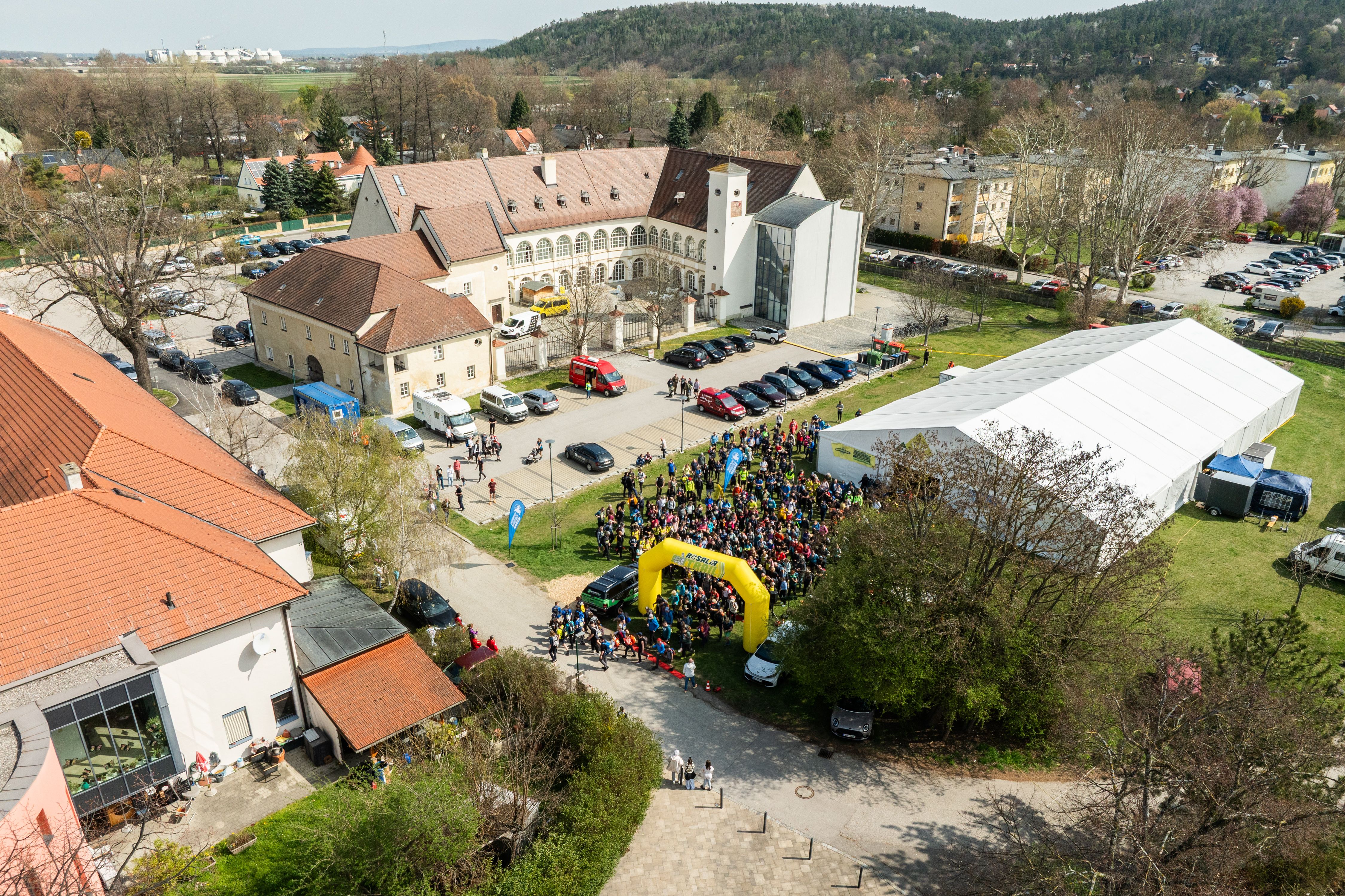 Aerial view of a castle with a crowd of people, tents and buildings during the Rosalia Trail Challenge.