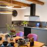 Modern kitchen with dining table set for four and stylish lighting.