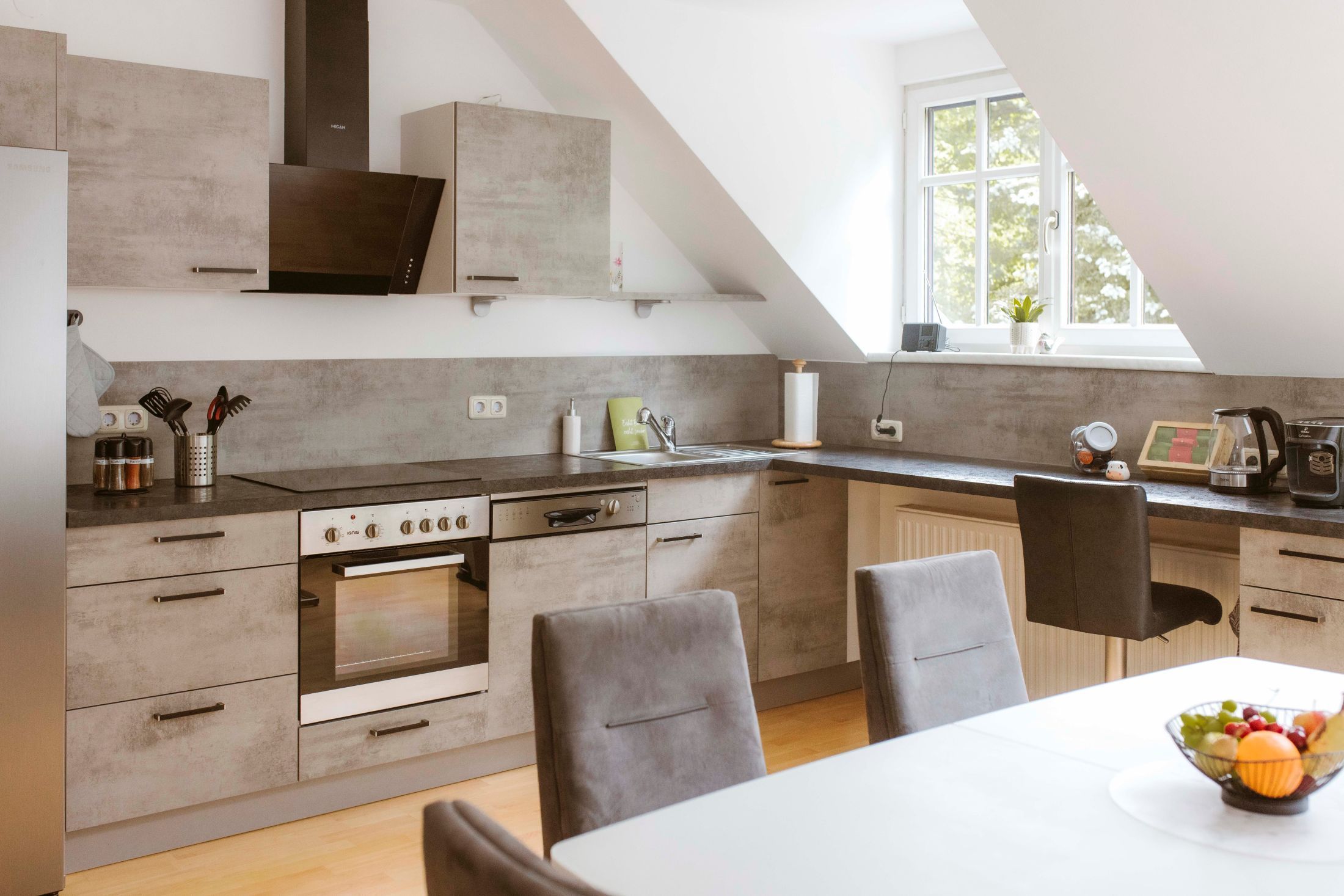 Modern kitchen with gray cabinets, dining table and fruit bowl.