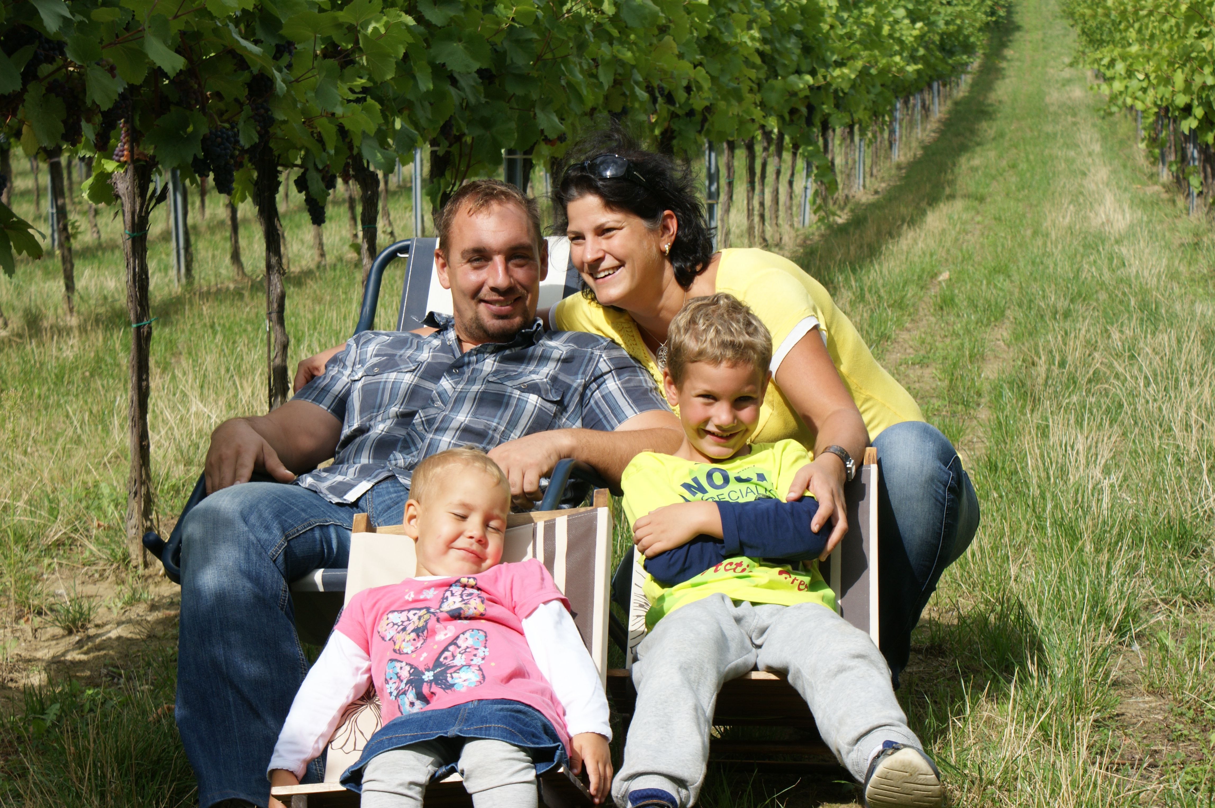 Family sitting on deckchairs in a vineyard.