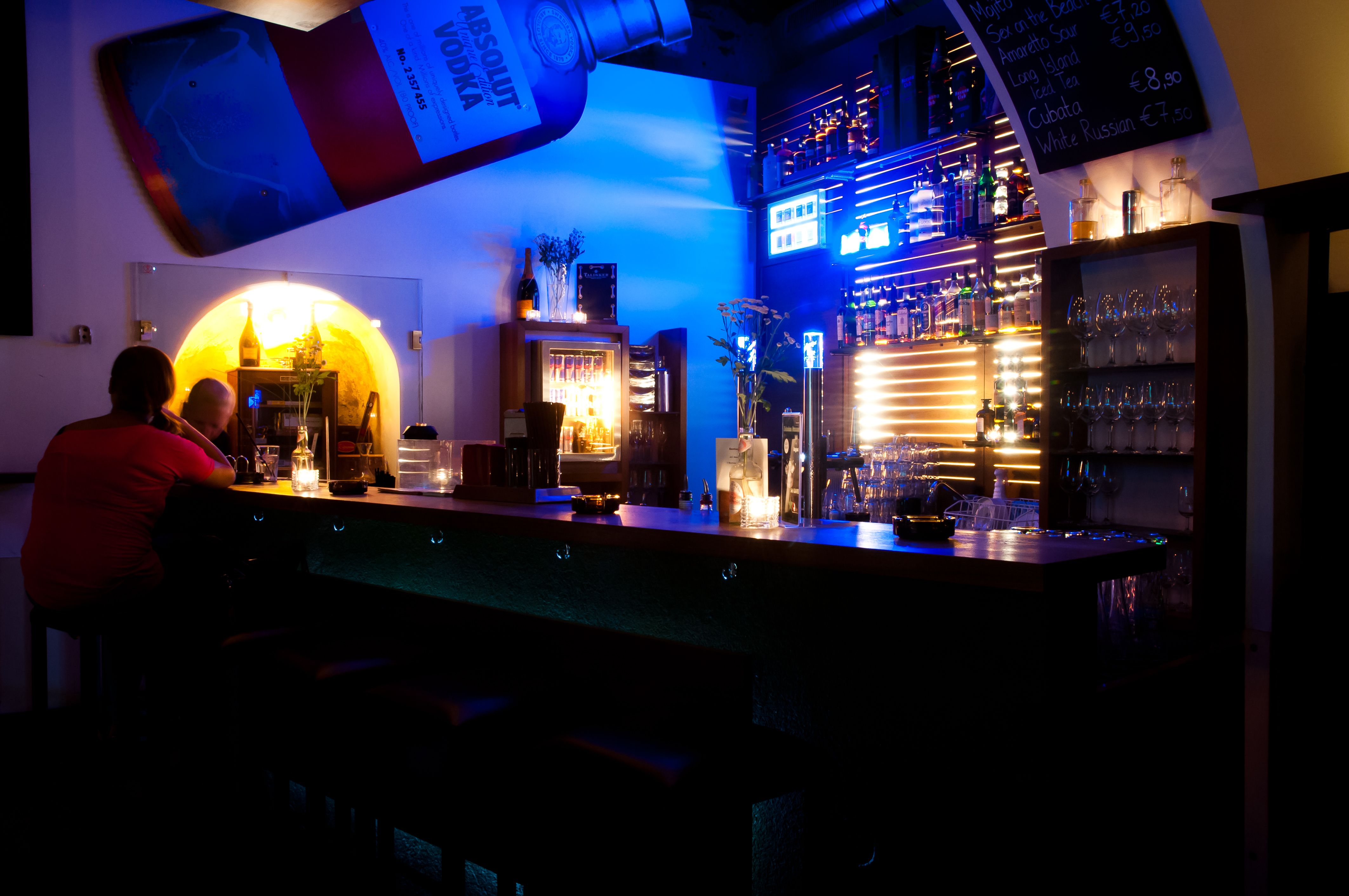 Interior view of a bar with blue lighting and bottle racks.