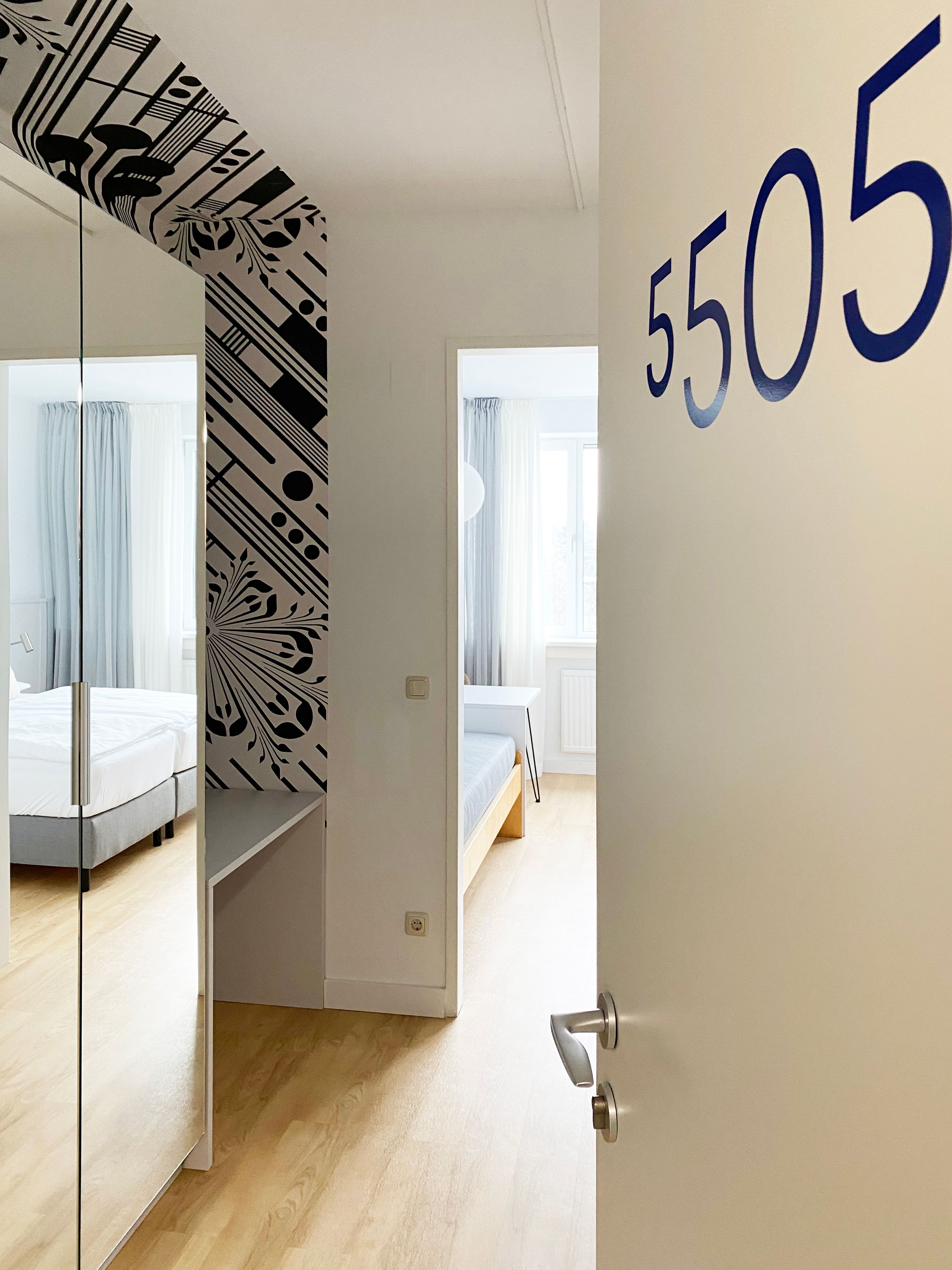 View of a guest room with the number 5505, modern furnishings with bed and mirror.