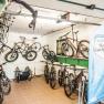Interior view of a bicycle garage with several suspended and stationary bicycles and a blue banner of the Vienna Alps Cycling Hosts.