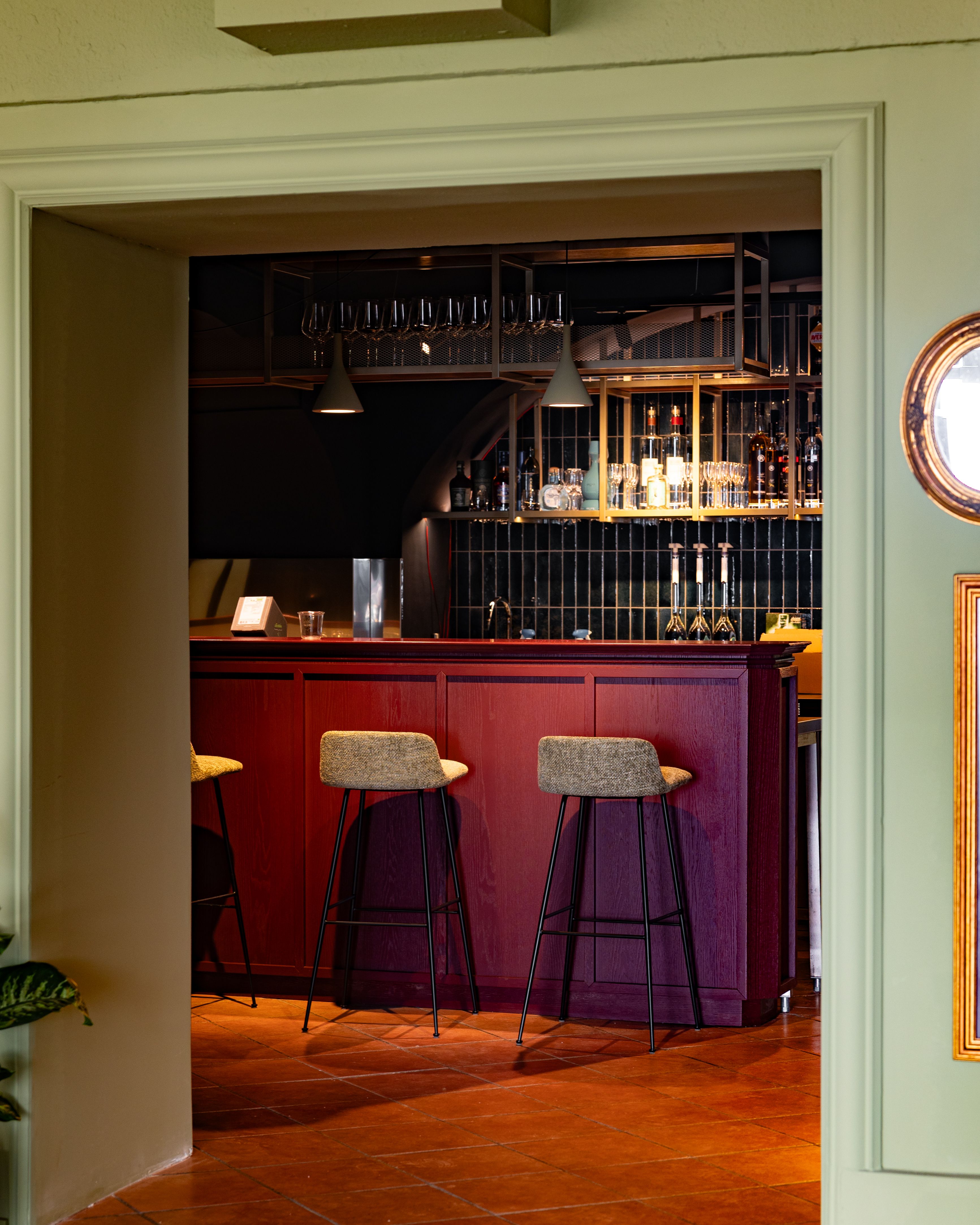 Elegant bar with red wooden furniture and high stools.