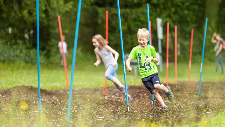 Children run through a course with colorful poles in the St. Corona motor skills park.