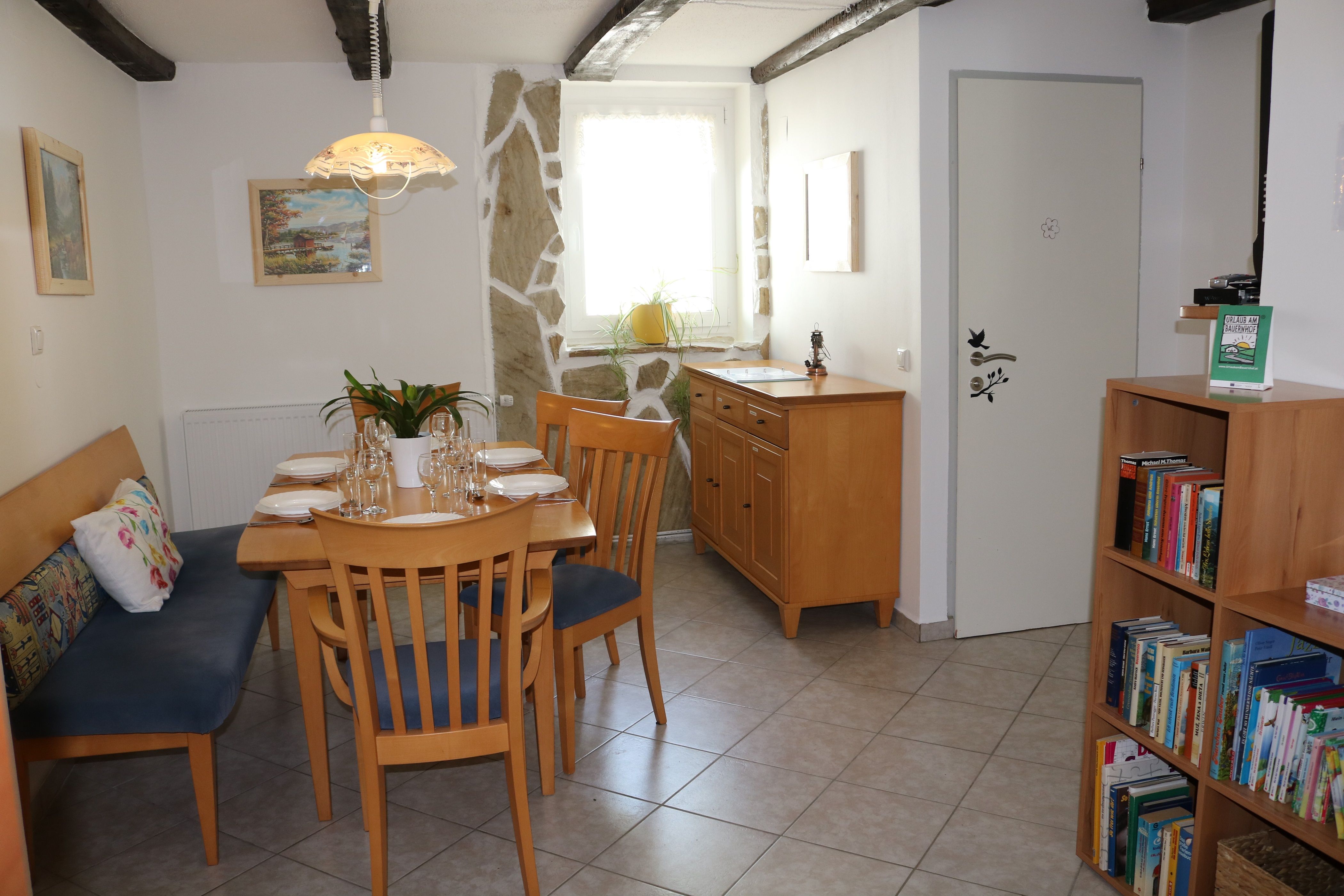 Dining area with wooden table, chairs and bookshelf.