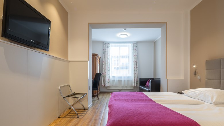 Hotel room with double bed, TV and seating area.