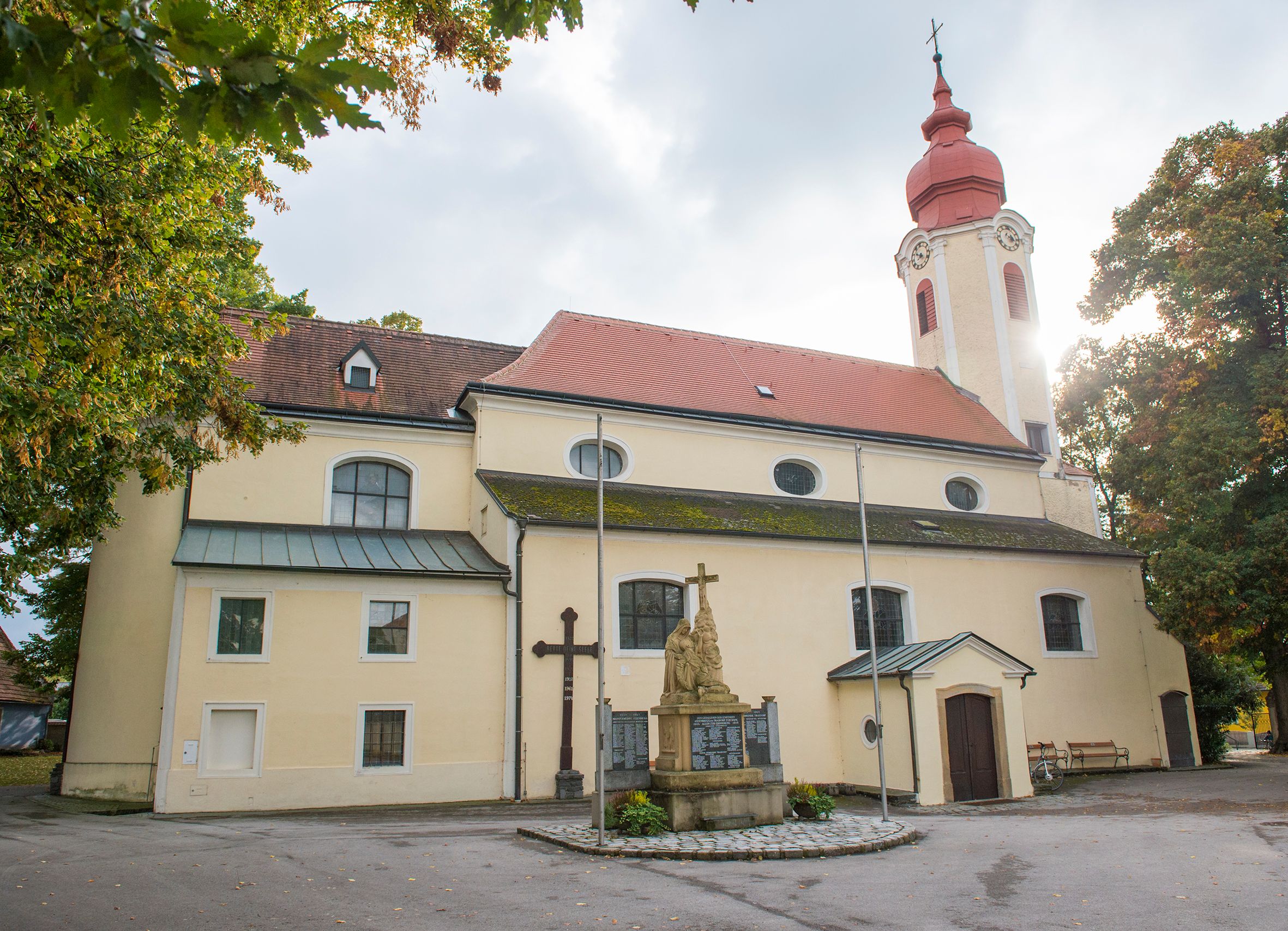 Heiligeneich parish church with statue and cross in the foreground.