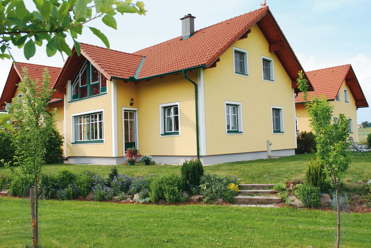 Yellow detached house with red roof and well-kept garden.
