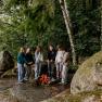 Group of young people standing around a campfire in the forest.