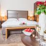 Double room at Hotel Schneeberghof with bed, roses, sparkling wine and strawberries.