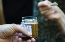 Ein köstliches Glas frischer Aufstrich wird in der Hand gehalten, während die Natur des Wienerwaldes im Hintergrund erblüht. Die harmonische Verbindung von Genuss und Landschaft lädt dazu ein, die Seele baumeln zu lassen und die Schönheit der Umgebung zu genießen.