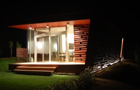 Modern building at night with illuminated terrace and glass front.