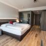 Modern hotel room with double bed, wooden floor and glass shower.