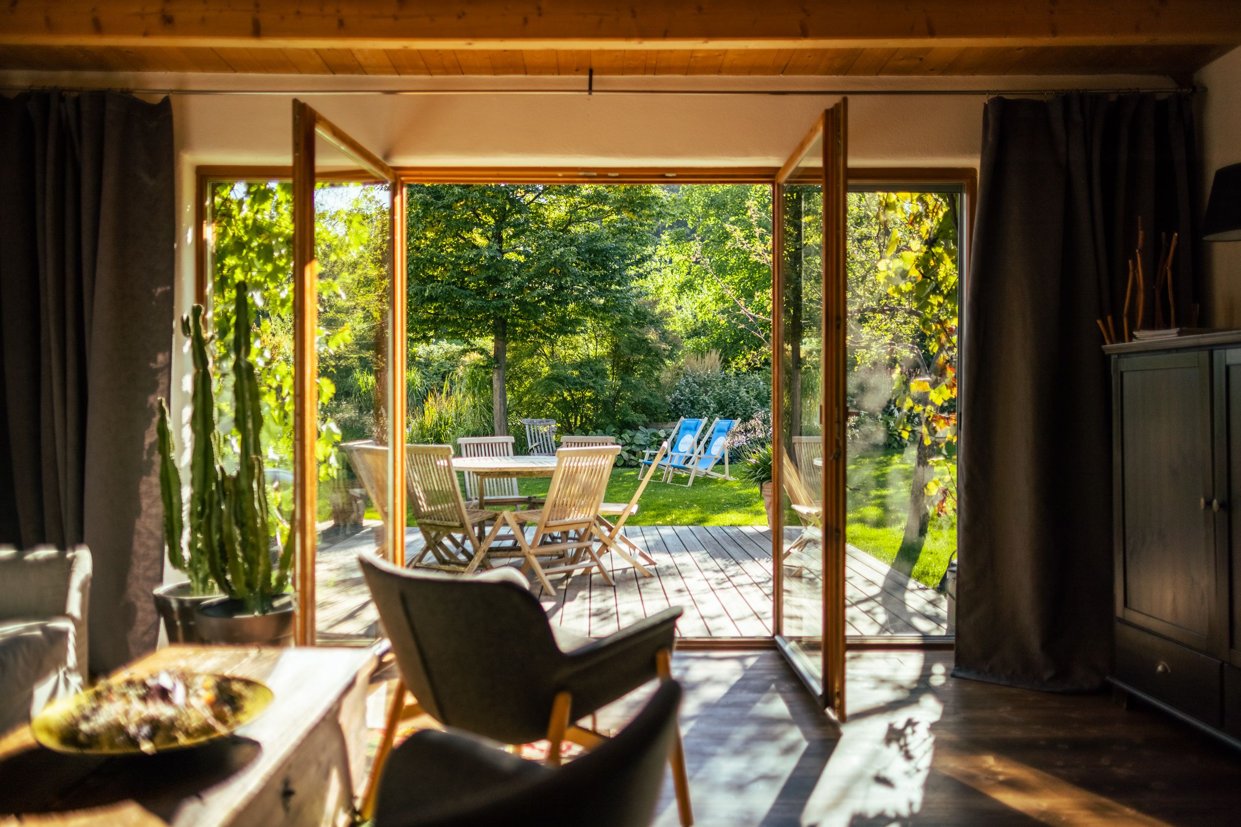 View from a living room onto a terrace with garden furniture and green garden.