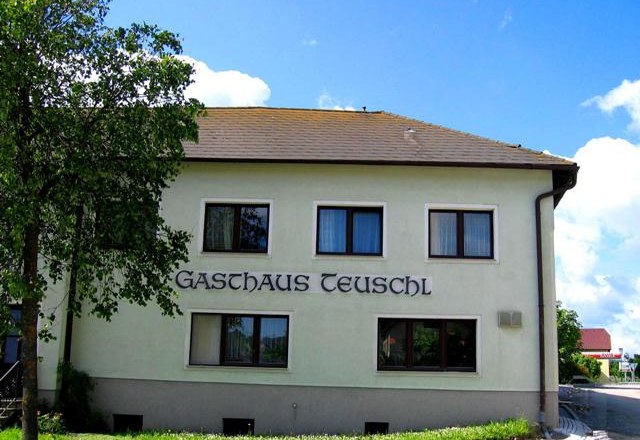 Exterior view of Gasthaus Teuschl with trees and blue sky.