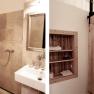 A bathroom with a shower, a washbasin and a wooden shelf next to a sliding door.